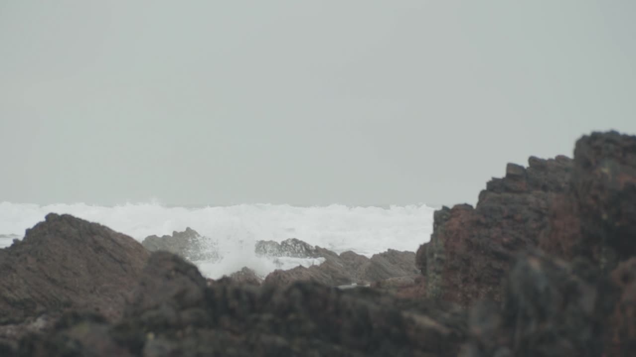 olas rompiendo en la playa con rocas en primer plano
