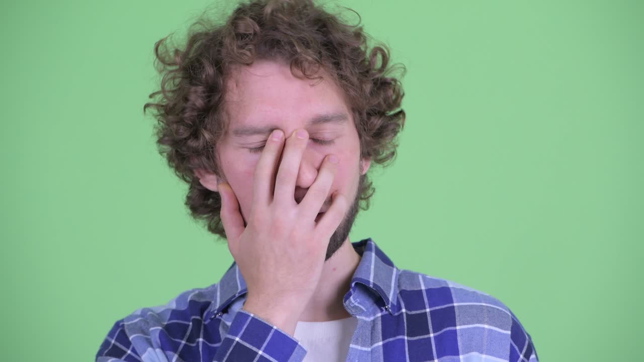 Young handsome bearded hipster man with curly hair