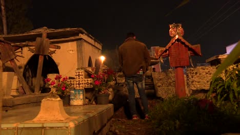 a man stand in front of a familar grave in cemetery of mixquic mexico during celebration of the day of the dead