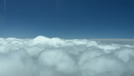 Eye-level-flight-forward-over-the-tops-of-clouds-with-a-blue-sky