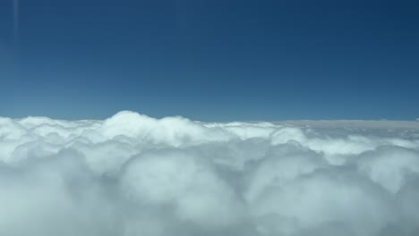 eye level flight forward over the tops of clouds with a blue sky