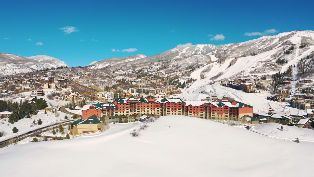 Flygfoto över skidstuga nära skidanläggning med snöklädda berg i bakgrunden i Steamboat Springs, Colorado