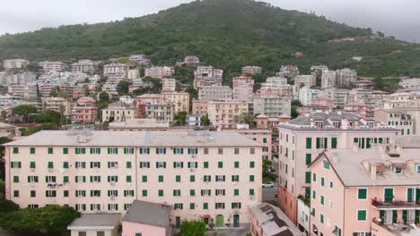 Edificios-De-Apartamentos-De-Génova-Con-Montañas-En-El-Fondo,-Vista-Aérea-Lateral