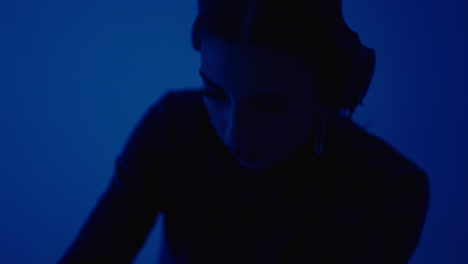mujer dj en un estudio oscuro con auriculares