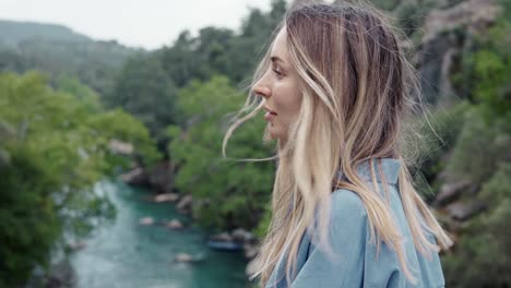 side view of woman tourist walks by the road bridge with view of green hills and river