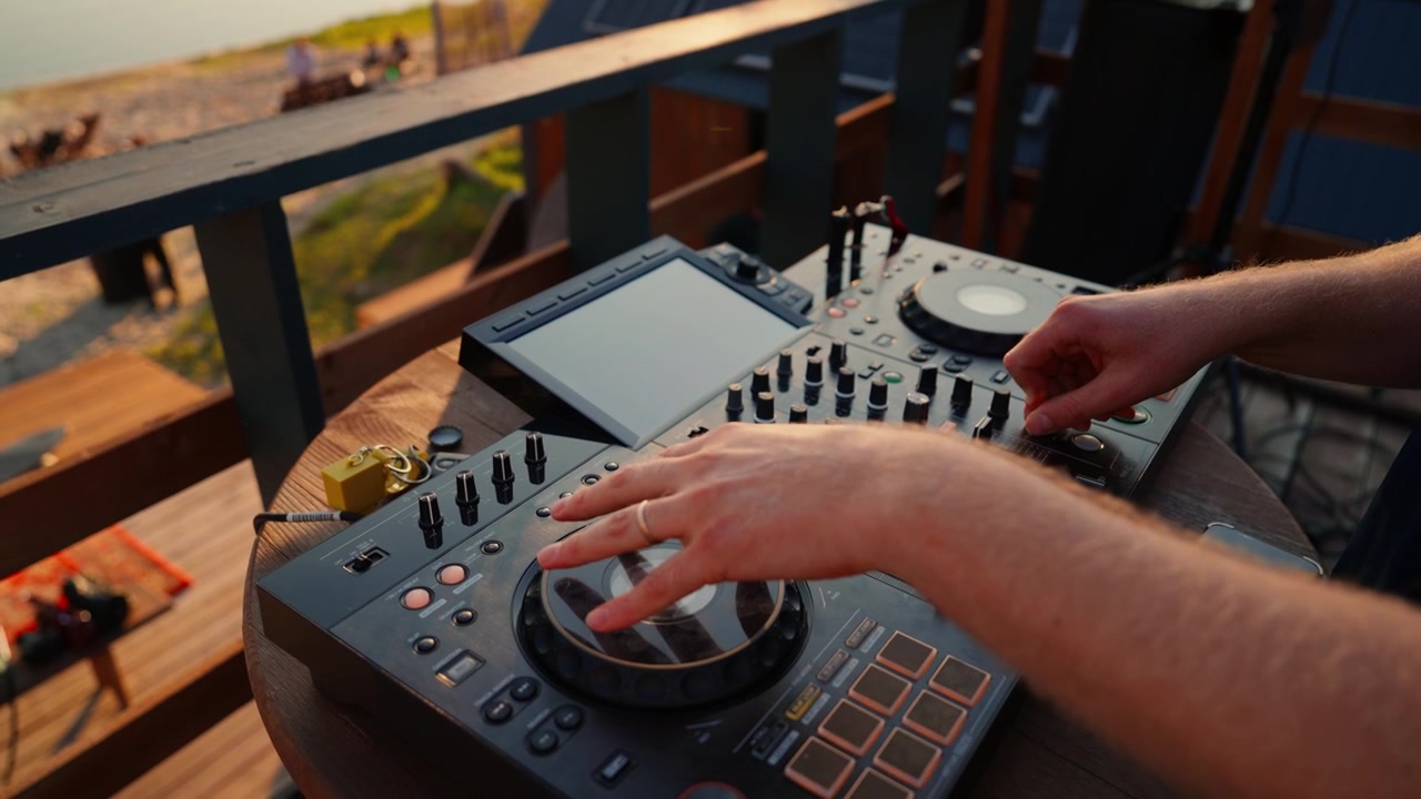 DJ che mixa musica su console a una festa al tramonto in spiaggia
