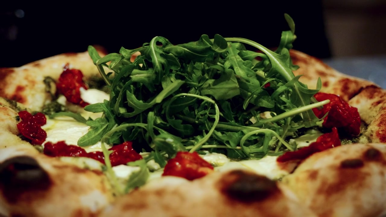 Processo autêntico de preparo de pizza em pizzaria italiana tradicional, com o chef adicionando coberturas na pizza