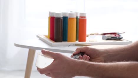 artist's hands mixing paint with a palette knife
