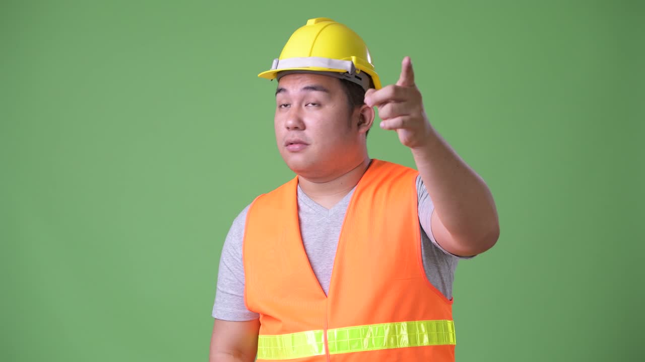 젊은 잘생긴 과체중 아시아인 남자 건설 노동자 초록색 배경