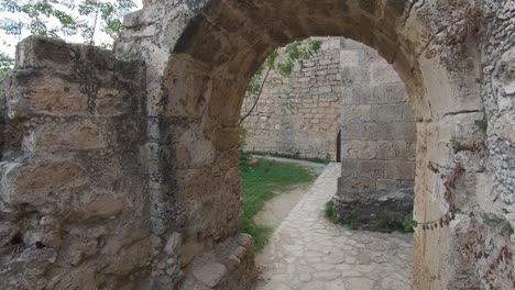 courtyard archway in kyrenia castle leading to path that runs along the stone wall - wide gimbal push in shot