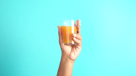 a hand holding a glass of orange juice