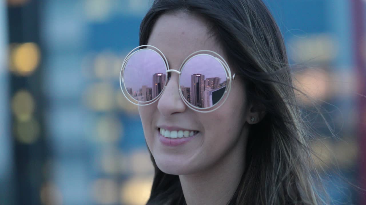 Girl wearing big round sunglasses outdoors in the evening smiling happy