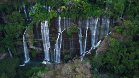 panoramic aerial pull away of large waterfall michoacán mexico covered with lushes green tree's surrounding the mountain