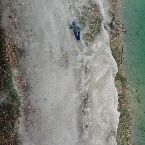 man walking along lake