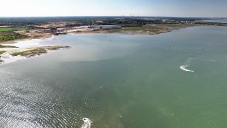 vista aérea sobre motos de agua dejando estela en el océano esmeralda acelerando a través de la costa de la central eléctrica de calshot