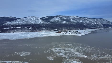 Aerial-drone-footage-of-an-icy-river-and-snow-covered-mountains-during-winter-in-America-in-the-Appalachian-mountain-range,-after-fresh-snowfall