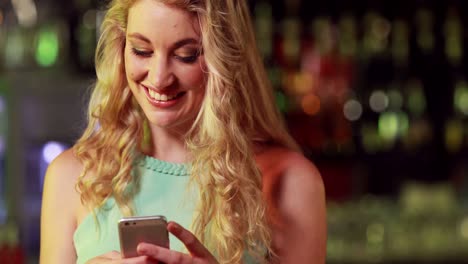 Smiling-woman-texting-in-bar-