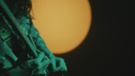long-haired guitarist playing rock music in dark studio