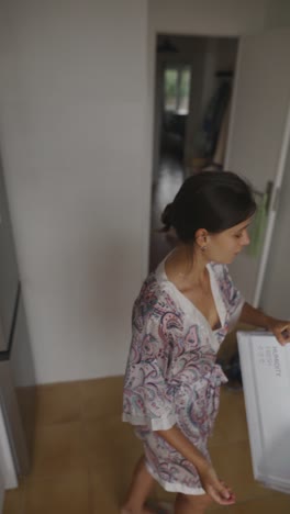 woman in kitchen opening refrigerator