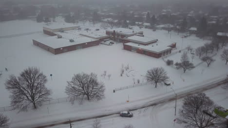 winter aerial view of a snow covered school in a residential community