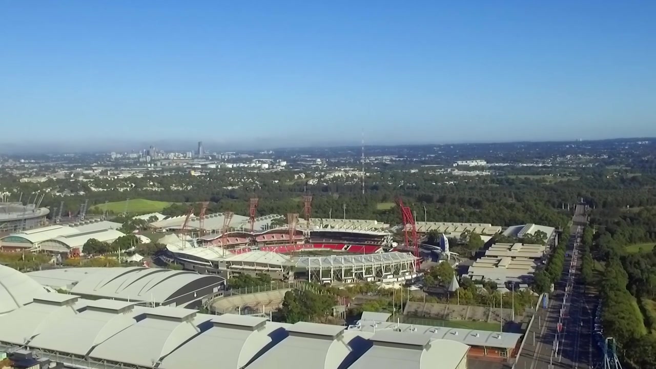 Luftfoto med drone som stiger, med utsikt over stadionene ved Sydney Olympic Park i Australia.