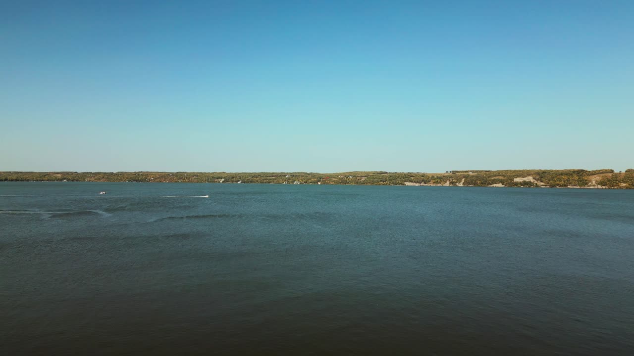 드론은 보트와 먼 해안으로 큰 호수 물체를 가로질러 날아갑니다.
