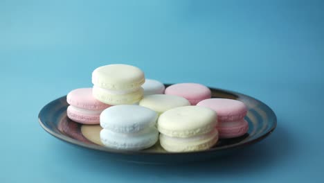 hand picking a colorful macaroon from a plate