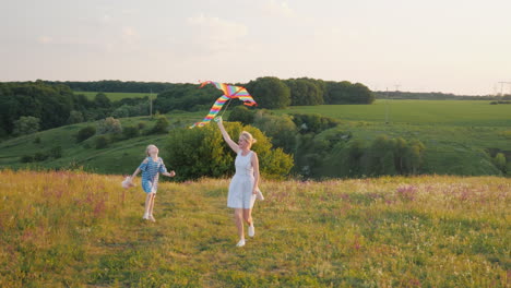 Mujer-Con-Una-Niña-Corriendo-Con-Una-Cometa-De-Aire-Feliz-Mamá-Con-Hija-Concepto-4k-Video-En-Cámara-Lenta