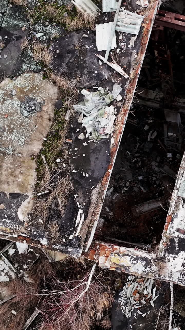 Debris left from an old industrial plant. Top aerial view of destroyed factory. Circle movement around the place. Vertical video