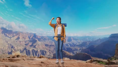 full body of asian female hiker with mountaineering backpack smiling and flexing her bicep while traveling at the top of mountain