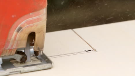 electric jigsaw in slow motion, sawing from left to right in a multiplex pine board