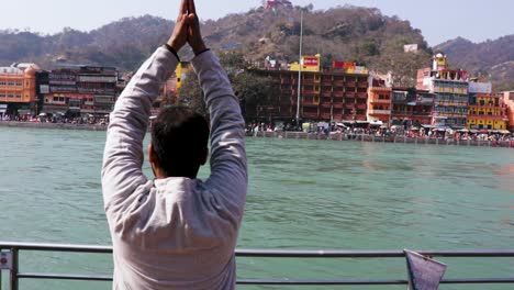 isolated young man prying the holy ganges river at river bank from flat angle video is taken at ganga river bank haridwar uttrakhand india