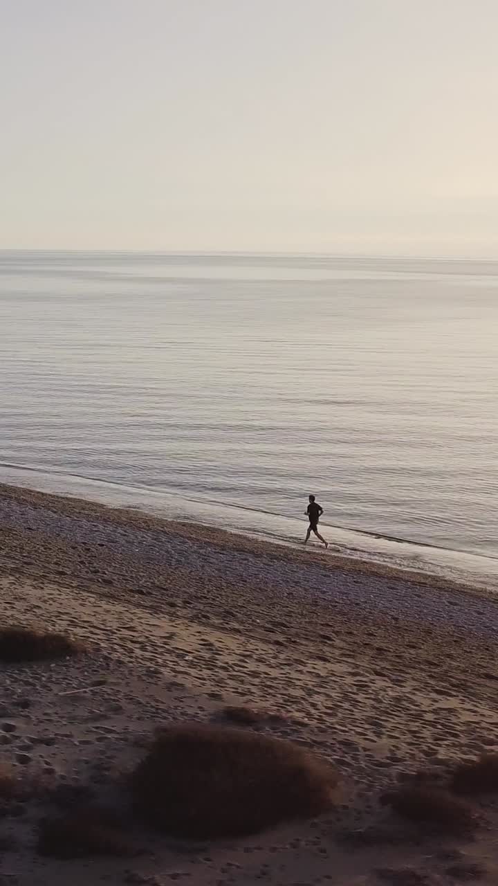 Man running on the beach. Orbital shot with drone