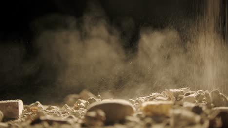 Close-up-Falling-dust-and-rocks-on-surface-Black-background-backlit,-slow-smooth-slider