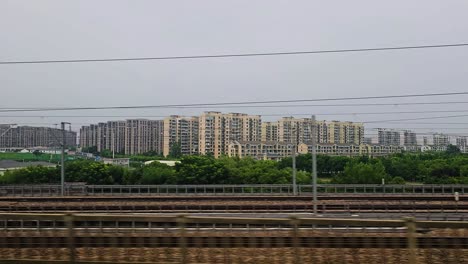 pov shot from a train window passing apartment buildings and industry in china