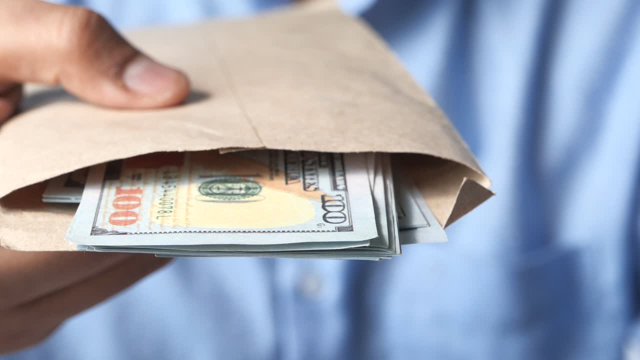 Person holder en kuvert fyldt med amerikanske dollars