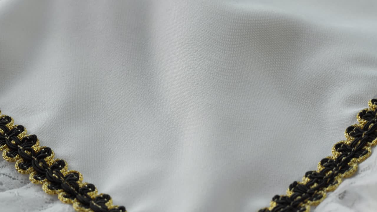 collar festivo. encaje blanco con decoración negra y dorada de primer plano. coser un vestido de novia. guipure ligero. sastrería hecha a mano, concepto de ropa profesional. fondo abstracto