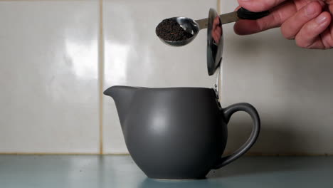 tea leaves poured or tipped into a modern pot in a household kitchen