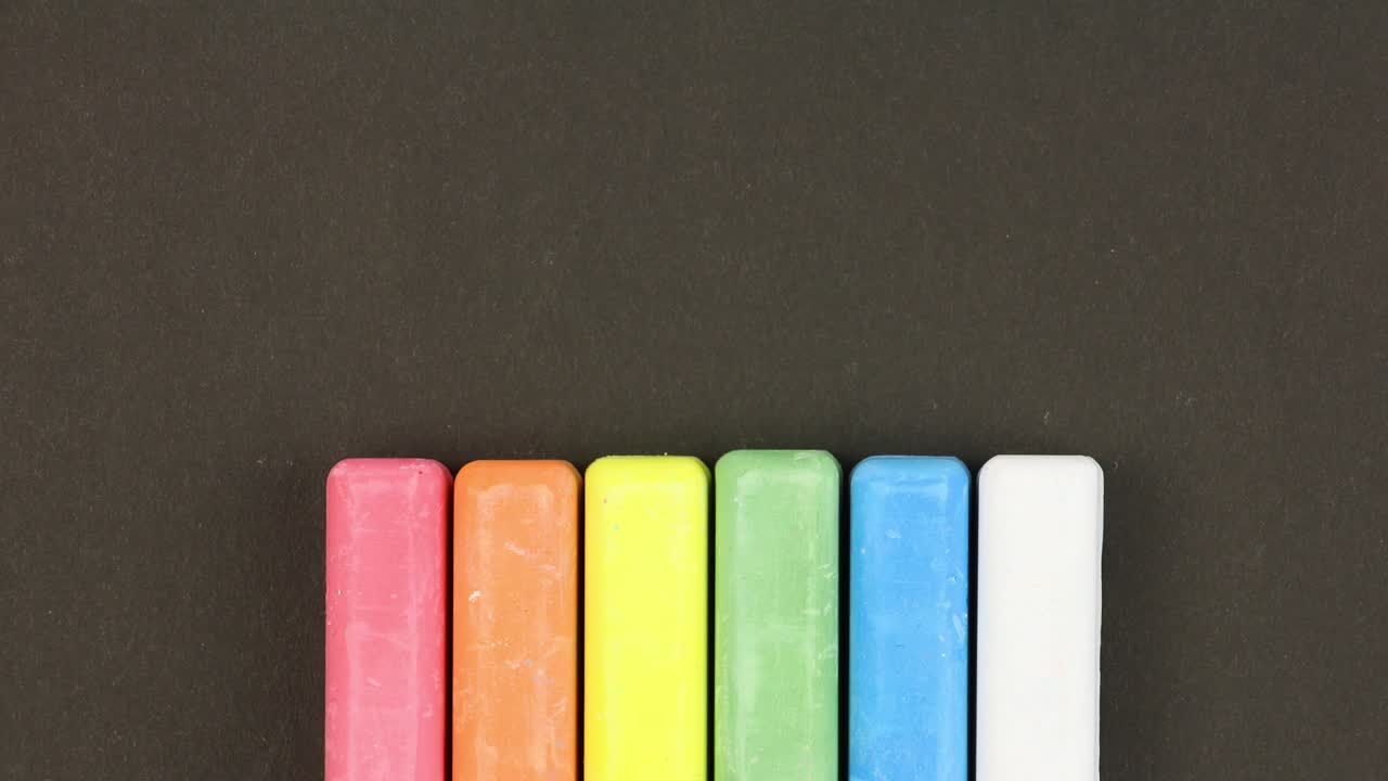 seis crayones de colores para niños en fondo negro alineados en fila, se elevan secuencialmente, primer plano, video en bucle, animación en stop-motion, concepto de educación de jardín de infantes