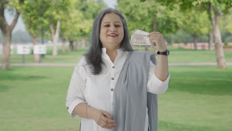 Happy-Indian-mother-using-money-as-fan-in-park