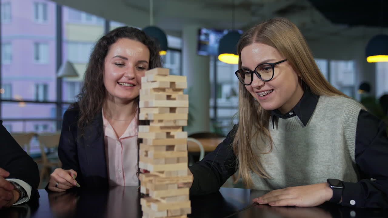 Break from work in the office. Office staff having fun and relax playing jenga at lunch break time. Blurred background.
