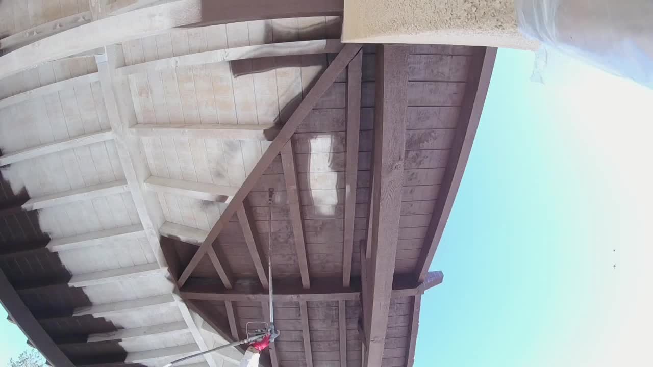 recubrimiento del techo del patio de madera con pintura exterior usando un rociador sin aire profesional