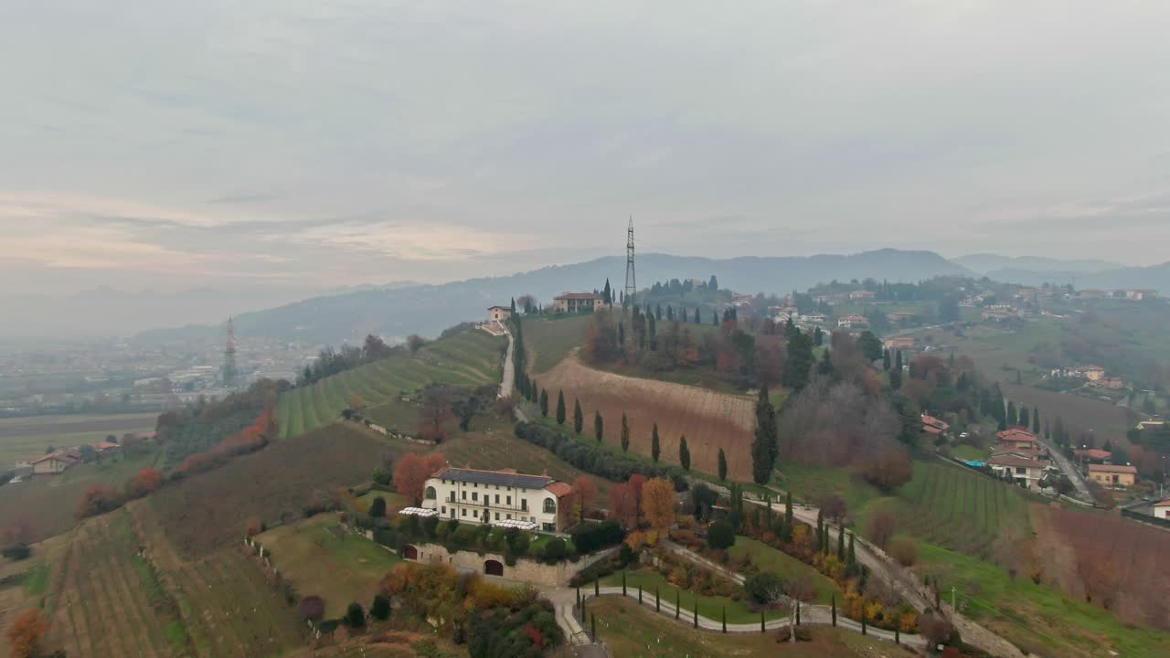 Drone footage moving in on the rolling hills and picturesque landscapes near Bergamo, Italy, on a gloomy fall day.