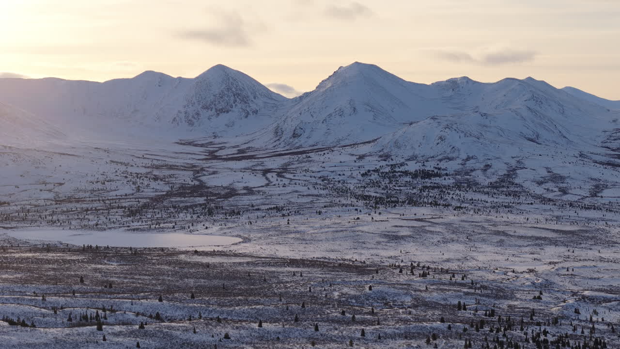 A cinematic aerial shot showcasing snow-covered mountains and the pristine Fish Lake landscape near Whitehorse, Yukon, capturing the raw beauty of Canada's wilderness.
