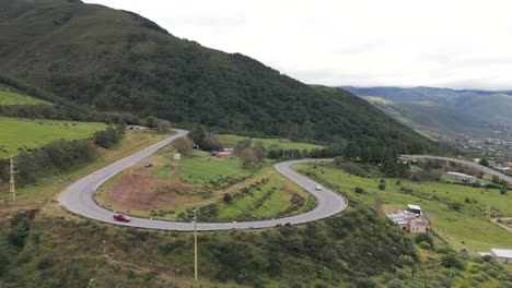 Round-street-curve-with-cars-in-the-beginning-of-the-hillside-of-the-mountains,-Province-of-Tucuman,-pan-shot-with-copy-space