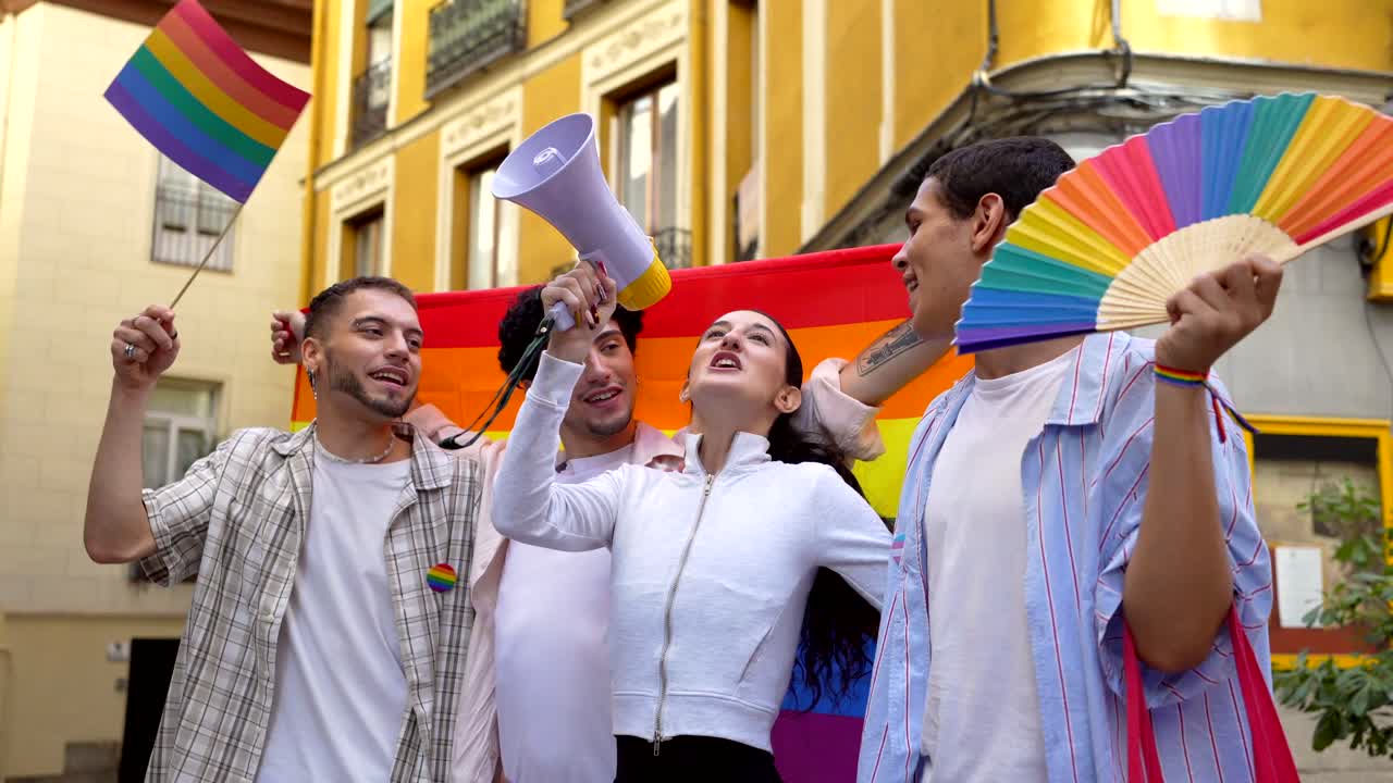 Group of LGBTQ people celebrating with pride flags and a megaphone on the street