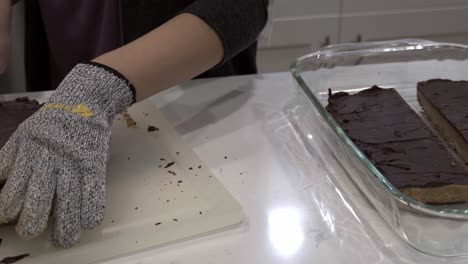 a young girl cuts the finished millionaire shortbread cookie into small pieces