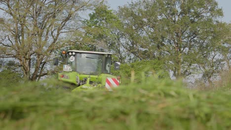 Vista-En-ángulo-Bajo-Desde-La-Hierba-De-Un-Tractor-Que-Se-Mueve-A-Través-De-Una-Pradera