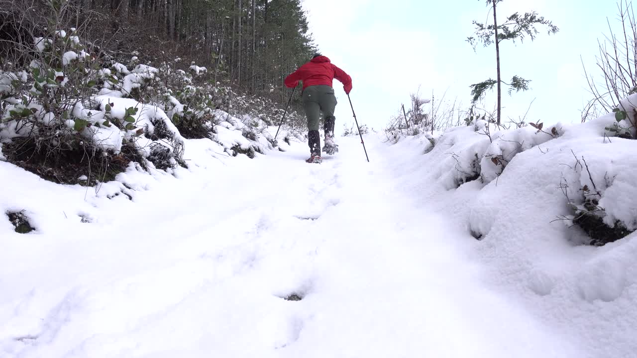 hombre subiendo con raquetas de nieve una colina empinada