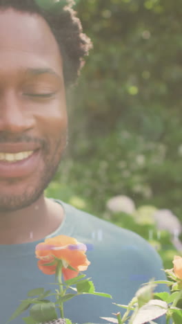 animation of glowing lights over african american man smelling flowers in garden